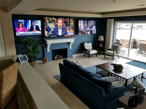 a living room filled with furniture and flat screen tvs on the wall