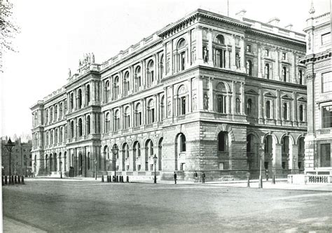 An Old Black And White Photo Of A Large Building On The Corner Of A Street