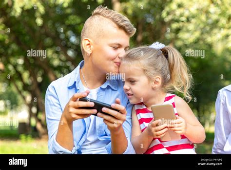 Cute Childs With Phones Sitting Outside And Using A Gadget Brother