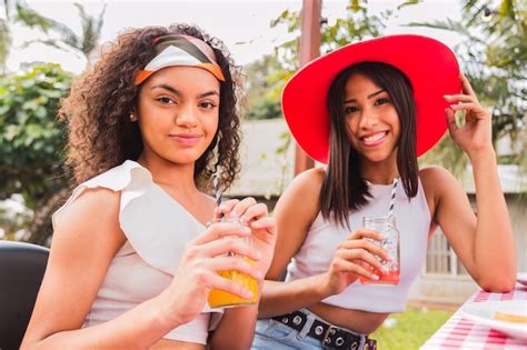 Retrato de jóvenes amigos bebiendo jugo dos amigas morenas disfrutando