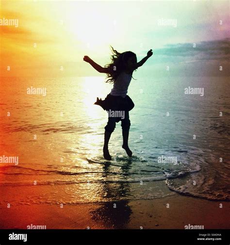 Silhouette Of A Little Girl Jumping Up And Down In The Water On The