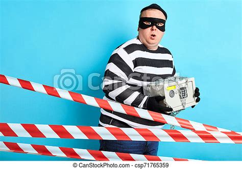 plump fat man with striped clothes in mask and hat carring safe close up portrait canstock