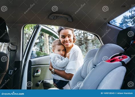 Smiling Mother Putting Baby Daughter in a Car Seat Stock Image - Image