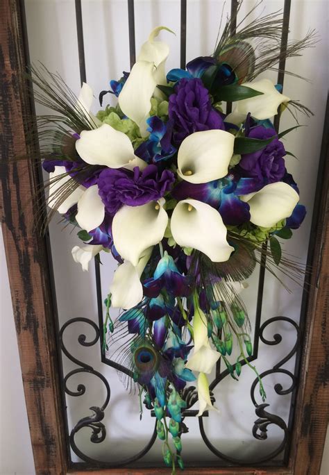 peacock feathers accent this cascade with teal orchids and white mini calla lilies peacock