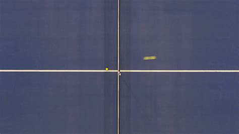 top-view-of-indoor-court-with-yellow-tennis-ball-flying-from-left-to-right-and-backwards