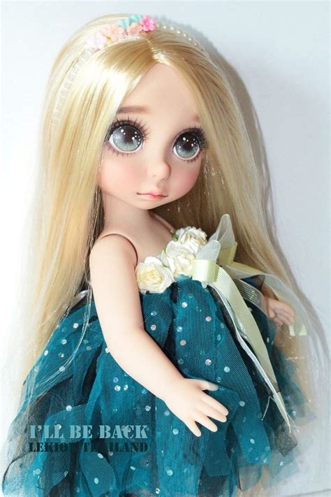 A Doll With Long Blonde Hair Wearing A Blue Dress And Holding A Flower