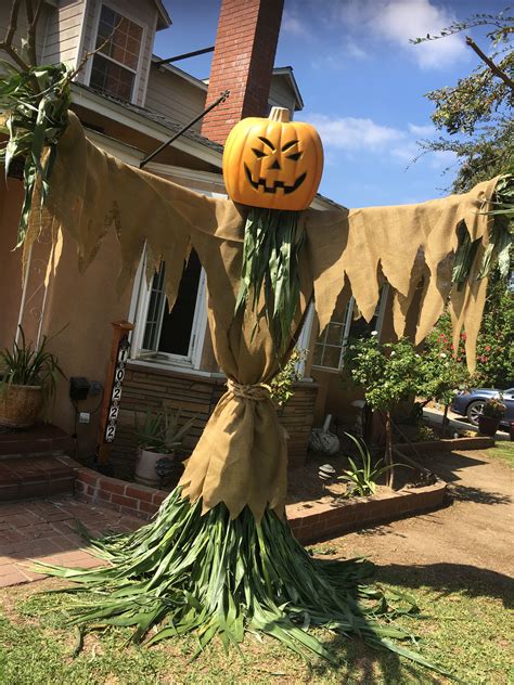 A Scarecrow Made Out Of Grass With A Jack O Lantern On Its Head