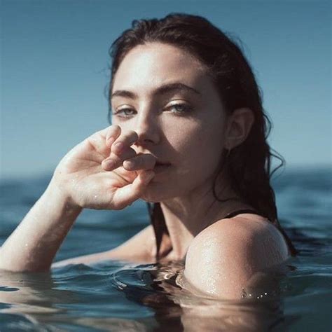 A Woman Is Floating In The Water With Her Hand On Her Face And Looking
