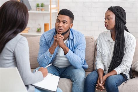 Couple Listening To Counselors Advice Sitting On Sofa During Therapy
