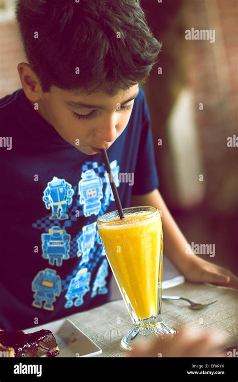Portrait Of Boy Drinking Orange Juice Using Drinking Straw Stock Photo
