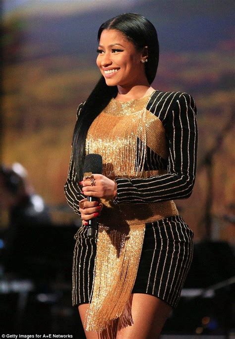 A Woman In A Gold And Black Dress Holding A Microphone
