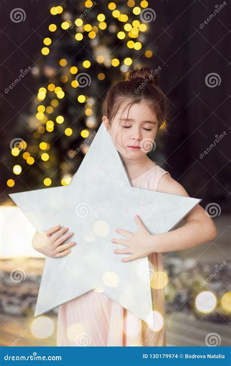 Child Holds A Star On The Background Of A Christmas Treegirl Dreaming