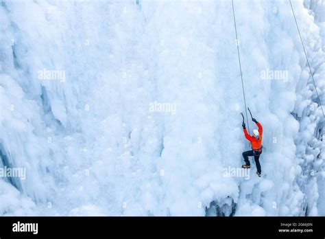 Aerial View Of A Frozen Waterfall And Rocks With Climber Ascending Its