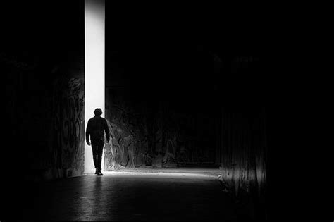 A Man Standing In The Middle Of A Dark Tunnel With His Back To The Camera