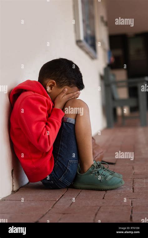 Sad Schoolboy Sitting Alone On Floor In Corridor Stock Photo Alamy