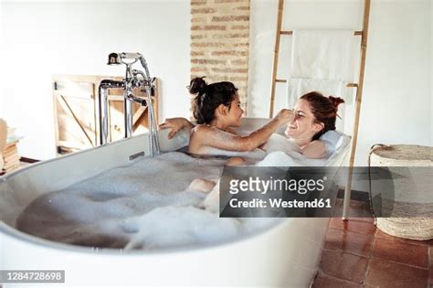 Mother And Daughter Playing While Taking Bath In Bathtub At Home High