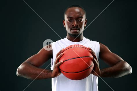 African Man Holding Basketball Ball Over Black Background Royalty Free