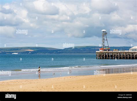 Woman Walking Along Bournemouth Beach With Pier And Views To The