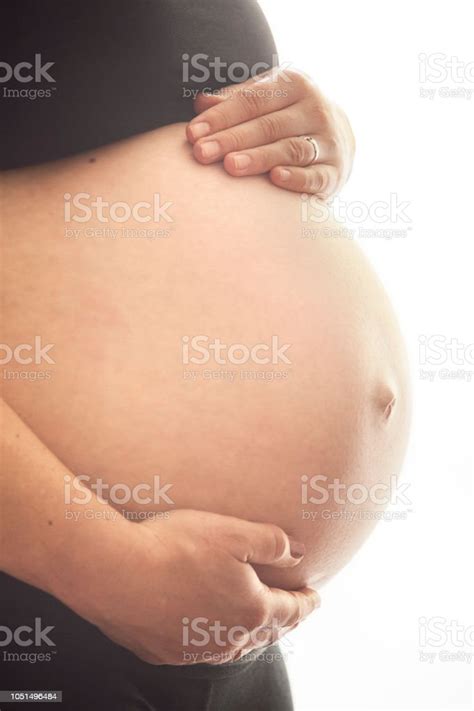 Close Up Of A 9 Months Pregnant Woman Holding Her Belly On A White