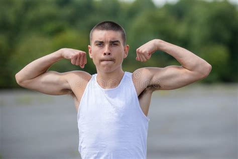 Um Adolescente De 19 Anos Flexionando Seus Bíceps Em Um Parque Público