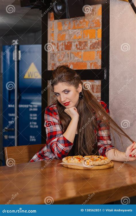 Beautiful And Girl Sitting At A Table With A Pizza In A Cafe Stock