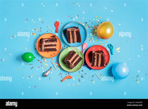 Chocolate Birthday Cake Slices On Plates Candles Balloons And Confetti On A Blue Table Above