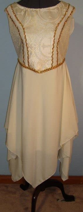 A White Dress With Gold Sequins On The Neckline And Sleeves Sitting On A Mannequin