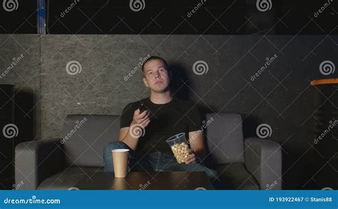 Handsome Man Eating Popcorn And Watching TV At Home Using Remote
