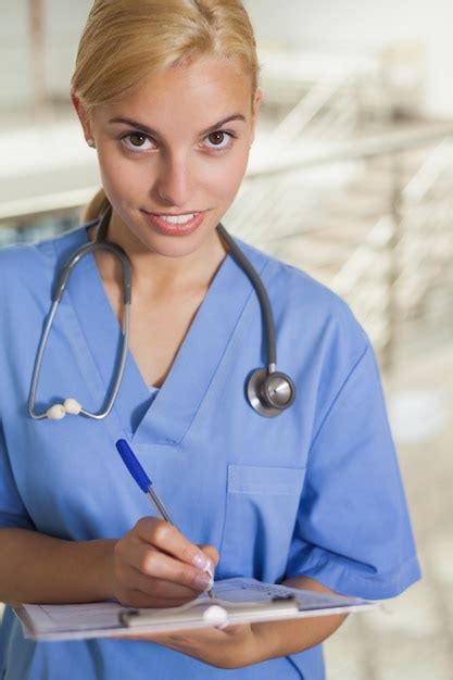 Premium Photo Nurse Writing On A Clipboard While Looking At Camera