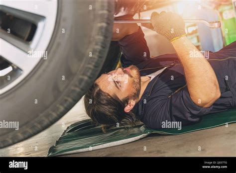 Mechanic Staff Worker Working Under Car Fix And Repair Tire Suspension