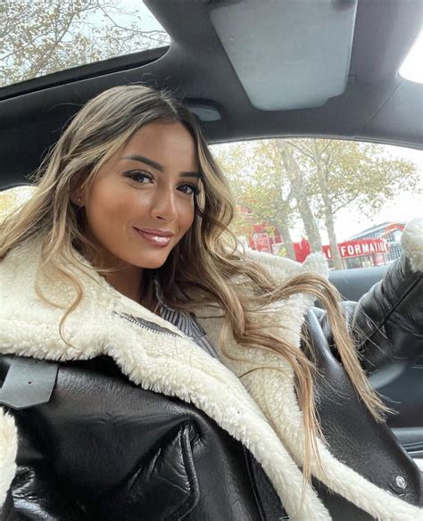 A Woman Sitting In The Back Seat Of A Car Wearing A Black Leather Jacket And White Fur Coat