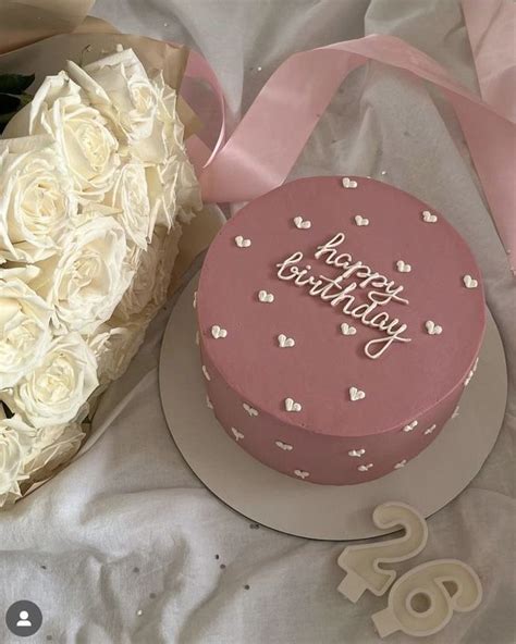 A Pink Birthday Cake Next To A Bouquet Of White Roses And A Heart