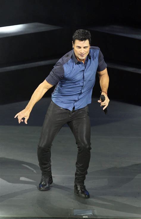 A Male In A Blue Shirt And Black Pants On Stage With His Hands Out To