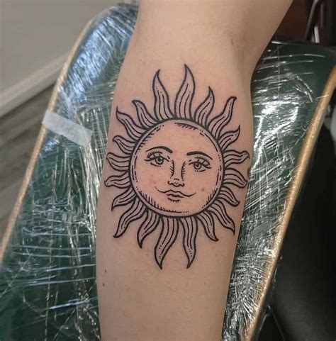 A Sun Tattoo On The Arm With A Face Drawn In Its Center Piece