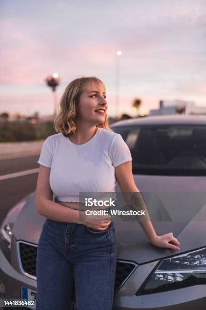 Hübsche Frau Mit Kurzen Blonden Haaren Die Sich An Ein Graues Auto Lehnt Und Lächelt Stockfoto