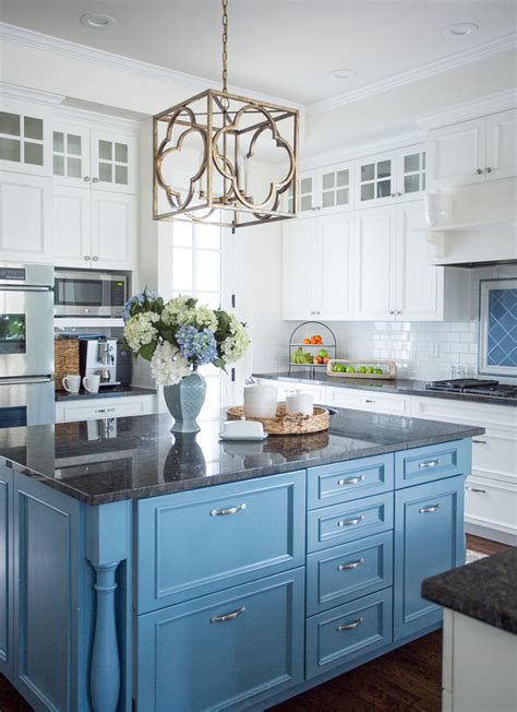 The white kitchen island truly stands out among the dark wooden cabinets and matching dark wood ceiling. Beach Inspired Home with Blue and White Kitchen - Home Bunch Interior Design Ideas