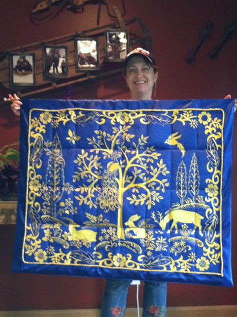 A Woman Holding Up A Blue And Yellow Quilt