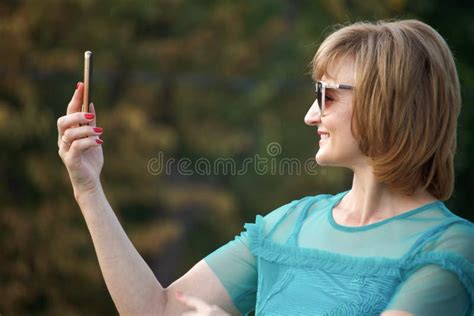 adult middle aged business woman on the street makes selfie on a smartphone selective focus