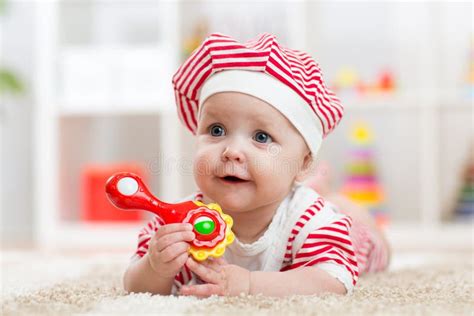 Baby Holding A Toy Lying On Carpet In Room Stock Image Image Of
