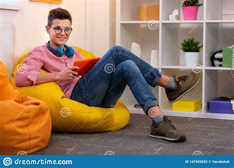 Modern Student In Glasses Sitting On Beanbag Chair Reading E Book Stock
