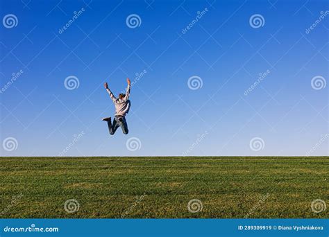 Happy Man Enjoying Fresh Air Jumping On The Horizon On The Green Grass