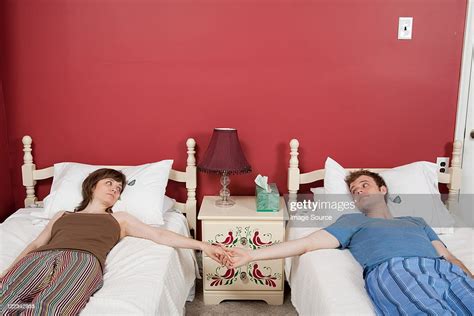 Young Couple Lying On Single Beds Holding Hands Photo Getty Images