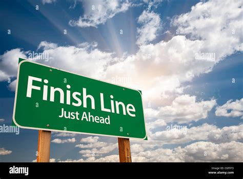 Finish Line Just Ahead Green Road Sign Over Dramatic Sky Clouds And