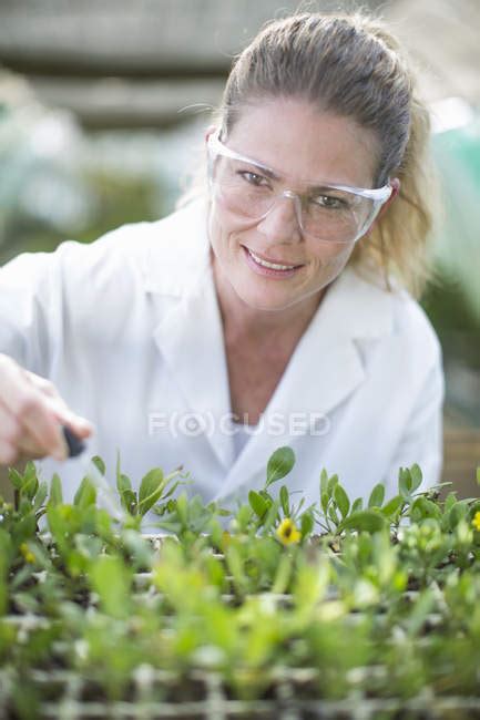 Portrait Of Female Scientist Pipetting Liquid Onto Plants Samples In