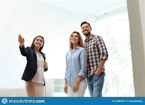 Female Real Estate Agent Showing New House To Couple Stock Image