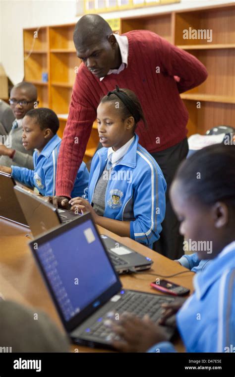 Teacher Helps South African School Children On Laptops During A