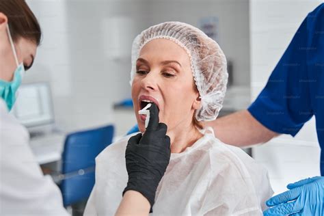 Attentive Nurse Spraying Anaesthesia At The Female Patient Mouth Before The Endoscopy Exam In