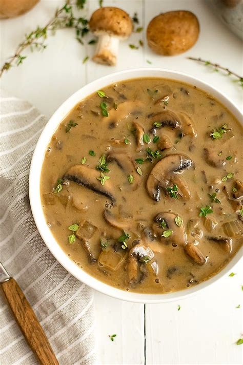 A White Bowl Filled With Mushroom Soup On Top Of A Table