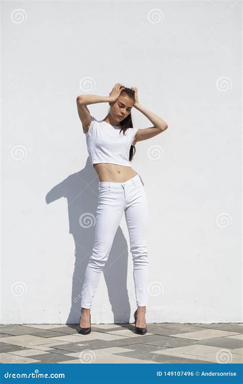 Model Tests Young Beautiful Brunette Model Posing Against A White Wall