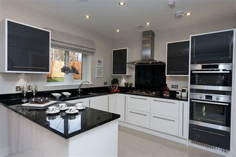 A Kitchen With Black Counter Tops And White Cabinets